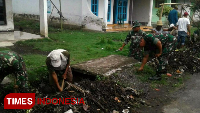 Bersama warga, personel Koramil 0821/13 Kunir bersihkan saluran air. (FOTO: AJP TIMES Indonesia)
