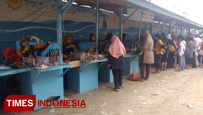 Para pengunjung sedang memedati sentra PKL yang berjualan ikan asap hasil tangkapan nelayan sekitar Wisata Pasir Putih (WPP) Dalegan, Kecamatan Panceng, Kabupaten Gresik, Jawa Timur, Senin (01/01/2018). (FOTO: Akmal/TIMES Indonesia)