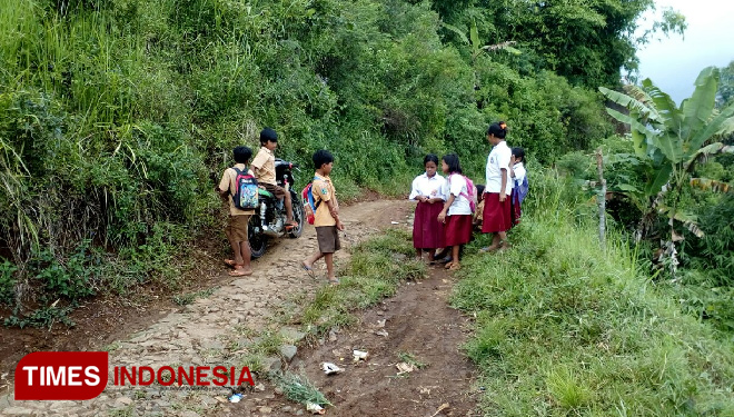 Anak-anak yang baru pulang sekolah melintas di jalan makadam yang menuju Selo Bonang. (FOTO: Dody/Times Indonesia)