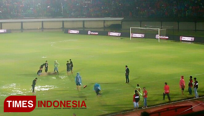 Panitia saat berupaya keras untuk mengeluarkan air hujan dari lapangan. Selasa (16/1/2018).(FOTO: Khadafi/TIMES Indonesia)
