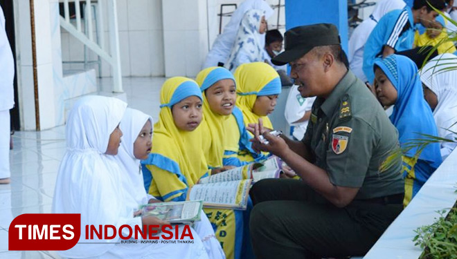 Salah seorang TNI Koramil Wringinanom sedang mendampingi siswi SD Muhammadiyah 1 Wringinanom membaca buku (FOTO : Akmal/TIMES Indonesia)