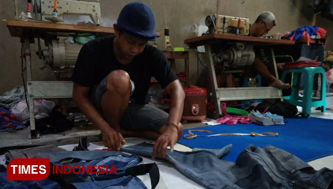 Abdul Qodir sedang mengubah celana jeans bekas menjadi tas (FOTO : Akmal/TIMES Indonesia)