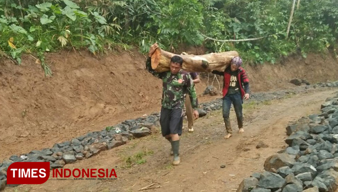 Serka Widyo, Satgas TMD saat membantu warga yang tengah membawa kayu hasil hutan yang akan digunakan untuk memperbaiki rumah (FOTO: AJP TIMES Indonesia)
