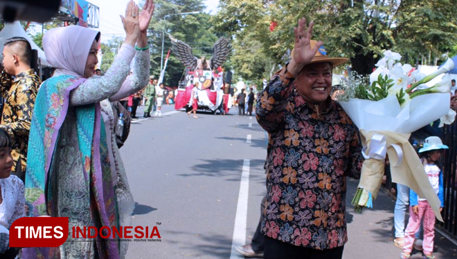Sambil membawa buket bunga, Wali Kota Pasuruan, H Setiyono, didampingi Wali Kota Batu, Dewanti Rumpoko, menyapa warga yang menyaksikan pawai budaya. (FOTO: Ferry/TIMES Indonesia)