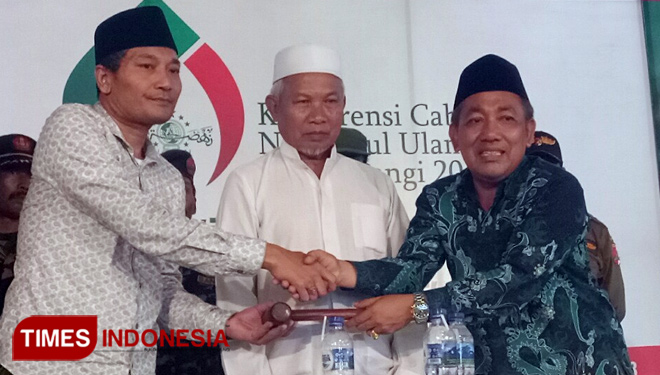 Pimpinan sidang, KH Misbahul Munir (kanan) saat memberikan palu sidang kepada KH Ali Makki Zaini, sebagai tanda pengembalian kepemimpin PCNU Banyuwangi. (FOTO: Erwin Wahyudi/TIMES Indonesia)