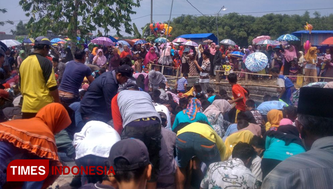 Warga berebut uang koin saat 'Udik-Udikan' saat tradisi Sedekah Bumi. (FOTO: Akmal/TIMES Indonesia)