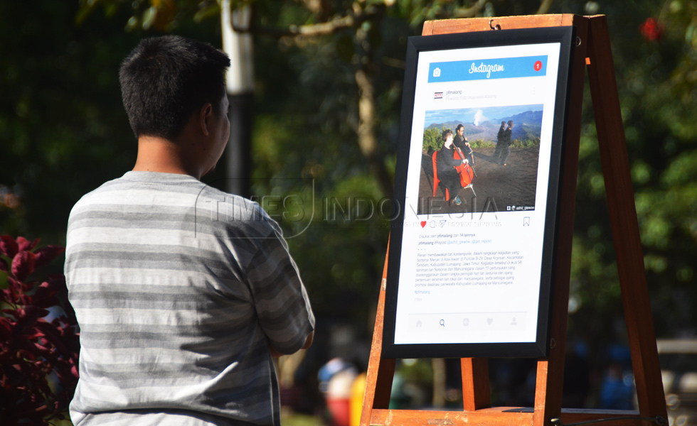 Warga melintas tak jauh dari karya foto yang dipamerkan oleh PFI Malang di Alun-alun Merdeka, kota Malang (FOTO : Adhitya Hendra/TIMES Indonesia)