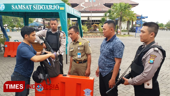Petugas bersenjata lengkap saat memeriksa barang bawahan warga yang akan mengurus administrasi kendaraannya di Samsat Lantas Polresta Sidoarjo. (FOTO: Rudi/TIMES Indonesia)