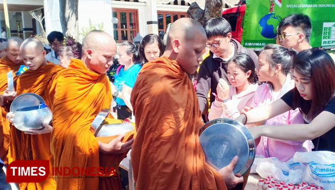 Umat Buddha memberi persembahan makanan kepada bhikkhu dan samanera. Kegiatan yang disebut Pindapata ini berlangsung di Padepokan Dhammadipa Arama, Kota Batu, Selasa (29/5/2018). (FOTO: Ferry/TIMES Indonesia)