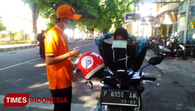 Petugas dari BPBD sedang membagikan masker ke pengendara di Jalan Ahmad Yani. (FOTO: Moh Bahri/TIMES Indonesia)
