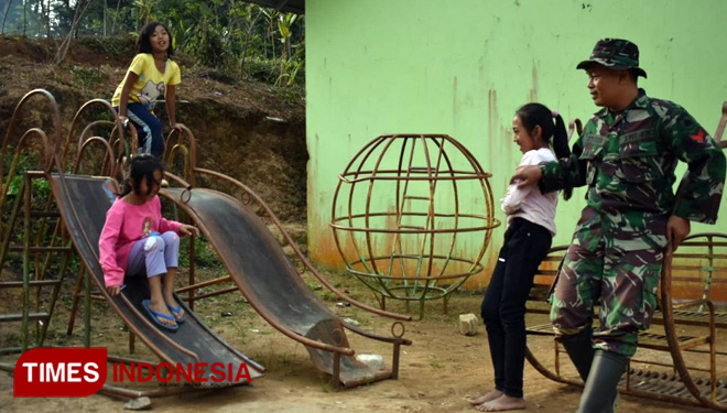Kopda Feri Ismantono, Satgas TMMD, yang menyempatkan diri menyapa anak-anak desa yang asyik bermain. (FOTO: AJP TIMES Indonesia)