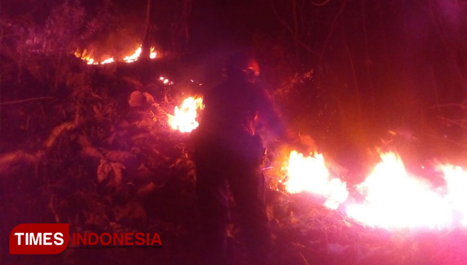 Petugas berusaha memadamkan api yang membakar lahan dekat permukiman warga di Ponorogo, Senin malam. (FOTO: Pamula Yohar C/TIMES Indonesia)