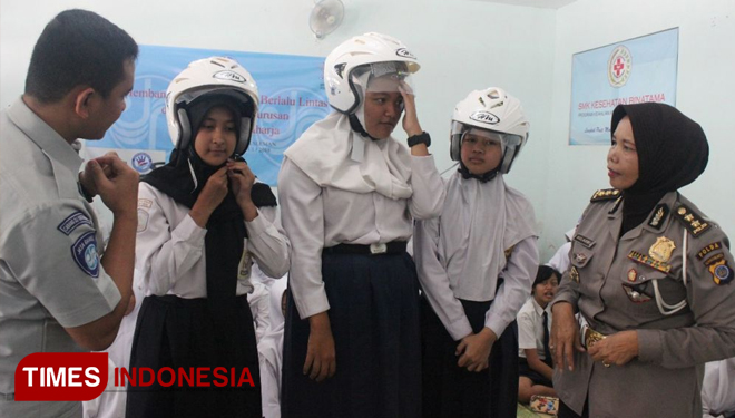 Kasubdit Dikyasa Polda DIY AKBP Sulasmi didampingi Pj Humas PT Jasa Raharja DIY Aryo W. Kusumo saat mengenakan helm pada siswa baru SMK Kesehatan Binatama Sleman, DIY, Senin (16/7/2018). (FOTO: A Riyadi/TIMES Indonesia)