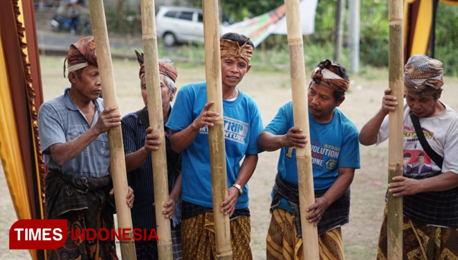 Lima pemuda sedang melakukan prosesi adat Minangin, yakni proses memisahkan padi dari tangkainya didalam Rantok (lesung perahu). (FOTO: Humas KLU for TIMES Indonesia)