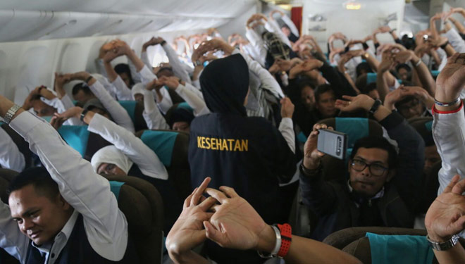 Petugas kesehatan haji memimpin senam peregangan untuk jemaah di pesawat (Foto: kemenag)