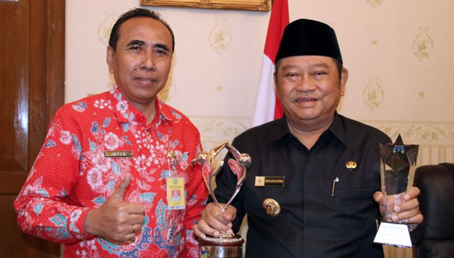 Bupati Sidoarjo H Saiful Ilah menunjukkan penghargaan Kota Layak Anak kategori Madya dan penghargaan Kabupaten Inisiator Pembentukan Unit Pelaksana Teknis Daerah Perlindungan Perempuan dan Anak (UPTD PPA). (FOTO: Istimewa)
