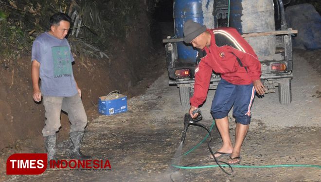 Peltu Siwiyono bersama Kades Pasegeran menyiram rabat beton di malam hari (FOTO: AJP TIMES Indonesia)