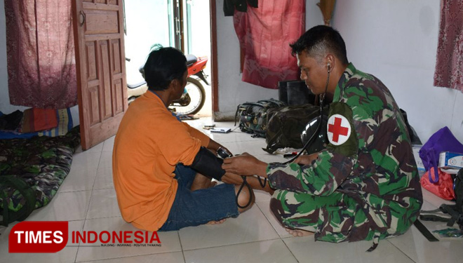 Anggota Keslap satgas TMMD sedang memeriksa Yatno (45) warga Pasegeran. (FOTO: AJP TIMES Indonesia)