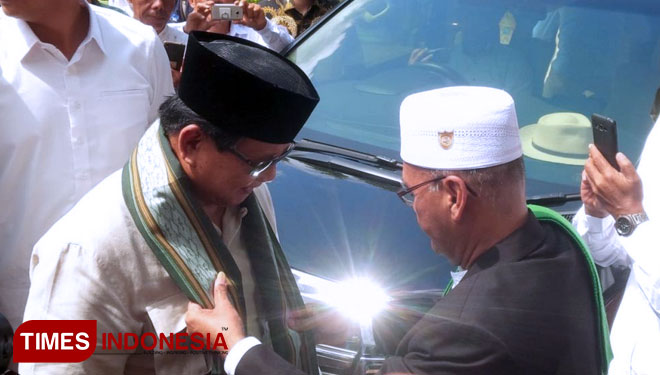 KH Hisyam Syafaat, pengasuh Ponpes Darussalam Blokagung, Banyuwangi, saat mengalungi surban Bacapres Prabowo Subianto. (FOTO : Syamsul Arifin/ TIMES Indonesia)