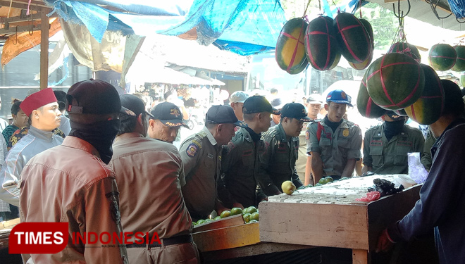 Anggota Satpol PP Bangkalan memindahkan lapak pedagang buah Pasar Blega ke titik yang telah ditentukan. (FOTO: Doni Heriyanto/TIMES Indonesia) 