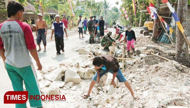 Warga dan satgas TMMD bahu membahu menyelesaikan pembangunan talud  (Foto: AJP TIMES Indonesia)