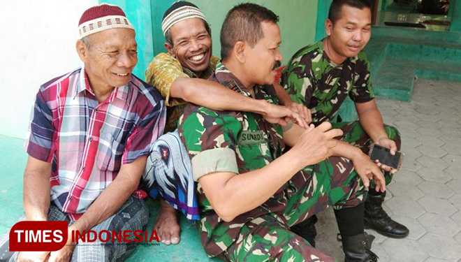 Personel TNI dan warga bersenda gurau saat waktu istirahat. (Foto: AJP Indonesia) 