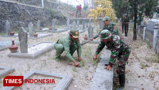Tak hanya kompak dalam pengerjaan sasaran fisik, satgas TMMD dan Linmas juga kompak membersihkan taman makam pahlawan. (FOTO: AJP TIMES Indonesia)