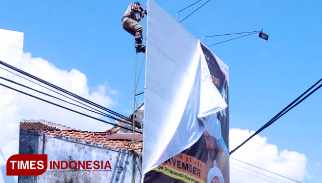 Satpol PP saat menurunkan Baliho milik Pemkab. (FOTO: Erwin Wahyudi/TIMES Indonesia) 