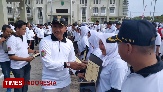 Bupati Pasuruan, HM Irsyad Yusuf menyerahkan penghargaan pada HUT ke-73 PGRI dan HGN tahun 2018, Sabtu (8/12/2018) di halaman Kantor Dinas Pendidikan Kabupaten Pasuruan. (FOTO: AJP/TIMES lndonesia)