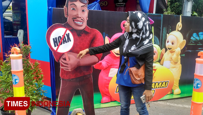 Salah seorang pengendara sedang berfoto bersama replikasi tokoh animasi Bang Jarwo yang terdapat di Pos pam Operasi Lilin Semeru 2018 Bondowoso (FOTO: Moh Bahri/TIMES Indonesia)