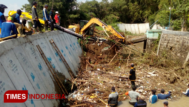 Tim BPBD dan Dinas PU kota Madiun bersihkan sampah sungai yang merusak jembatan yang menghubungkan makam, Jumat (11/01/2019). (Foto Ervan Marwantaka/TIMES Indonesia)