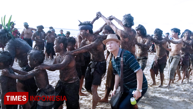 Tourists took selfie with the mebuug-buugan participants (Photo: Khadafi/TIMES Indonesia)