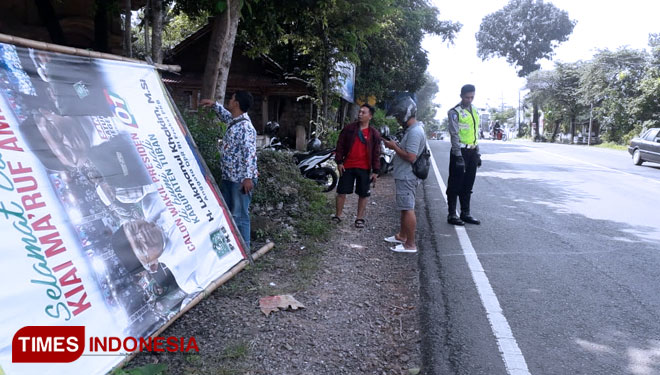 APK yang roboh dan petugas dari Unit Laka Satlantas Polres Tuban, menunjukkan titik lokasi robohnya APK Caleg DPR RI Lukmanul Khakim, Sabtu, (16/03/2019) (Foto: Achmad Choirudin/TIMESIndonesia)