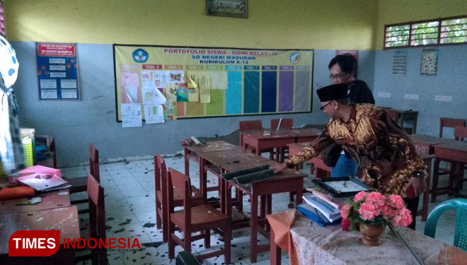 Nismudi, guru SDN Maduran, menunjukkan puing asbes yang menghantam kaca jendela ruang kelas, akibat terjangan puting beliung, Kamis (21/3/2019). (FOTO: MFA Rohmatillah/TIMES Indonesia)