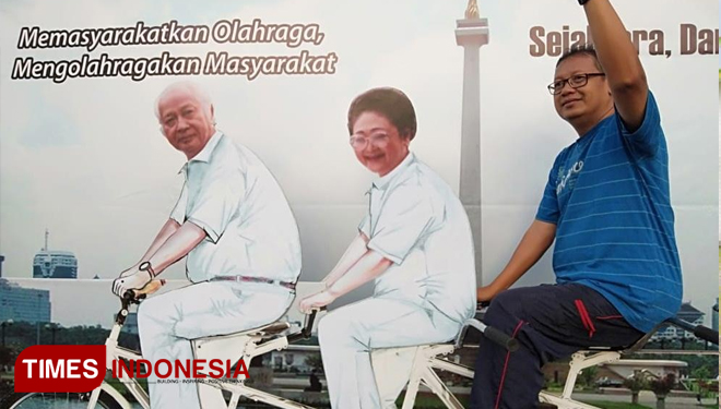 pengunjung berfoto bersama Titiek Soeharto di depan poster besar Pak Harto dan Ibu Tien bersepeda.