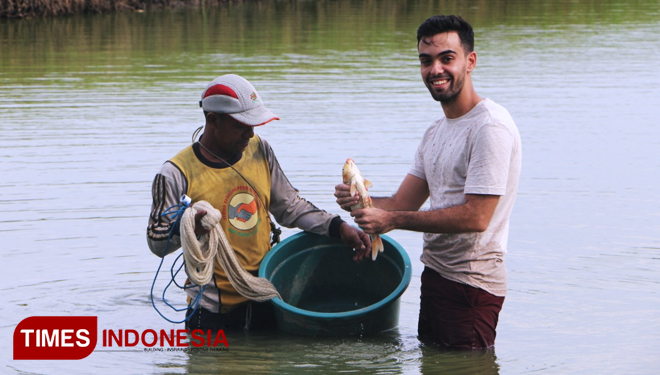 Joel ikut memanen ikan bandeng si lahan tambak (FOTO: Akmal/TIMES Indonesia).