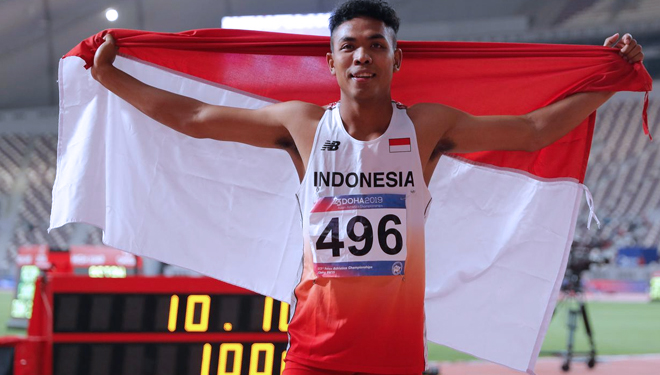 Pelari andalan Indonesia, Lalu Muhammad Zohri mengibarkan bendera Merah Putih usai tampil di Kejuaraan Atletik Asia di di Doha, Qatar, Senin (22/4/2019). (FOTO: AP/Vincent Thian)