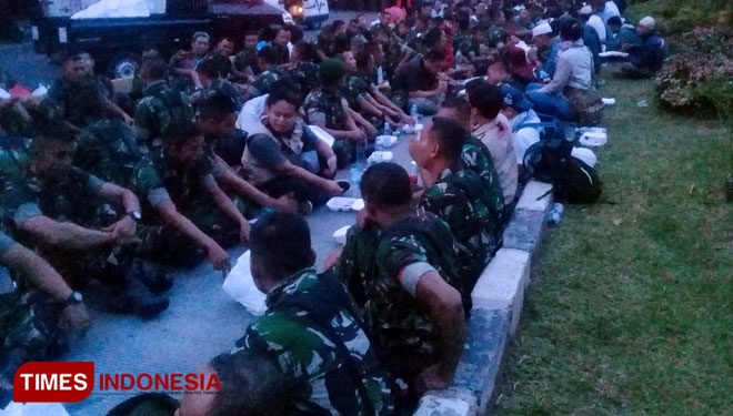 Personel TNI dan massa pendemo asyik berbagi dan berbuka bersama. (FOTO: Rizki Amana/TIMES Indonesia)