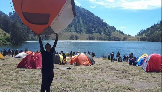 Salah satu pendaki berpose di balik pemandangan Danau Ranu Kumbolo, kaki Gunung Semeru, Kabupaten Lumajang, Jawa Timur, (Foto: Dhalcamping)