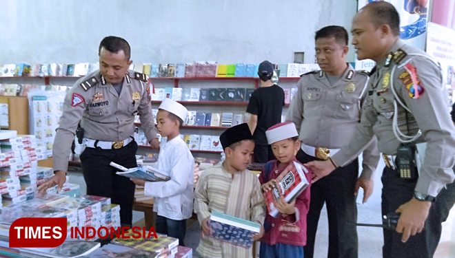 Polisi Gresik saat mendampingi anak yatim membeli alat sekolah (FOTO: Akmal/TIMES Indonesia)