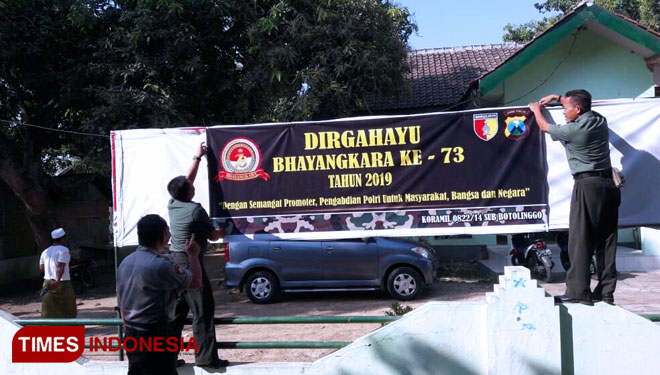 Prajurit TNI di Kabupaten Bondowoso gotong-royong pasang spanduk HUT ke-73 Bhayangkara. (FOTO: Moh Bahri/TIMES Indonesia)