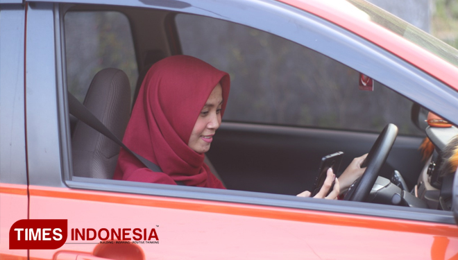 Rizky Aulia Hasyim di atas mobilnya ketika menunggu penumpang. (FOTO: Istimewa/TIMES Indonesia)