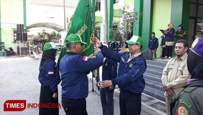 Rektor Unisla, Bambang Eko Muljono (topi hijau putih) menerima bendera Universitas sebagai tanda pelepasan peserta KKN, Senin (15/7/2019). (FOTO: MFA Rohmatillah/TIMES Indonesia)