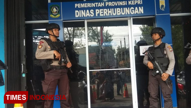 Anggota kepolisian dengan senjata Laras panjang berjaga ketat di depan Kantor Dishub Kepri. (FOTO: Ali Mahmud/TIMES Indnesia)