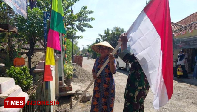 Anggota TNI Kodim 0712 Tegal memberikan Bendera Merah Putih dan membantu warga masyarakat memasangnya. (FOTO: AJP/TIMES Indonesia)
