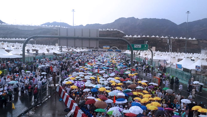 Para jemaah haji langsung menggelar payung begitunhujan deras mengguyur Mina. (FOTO : Kemenag) 