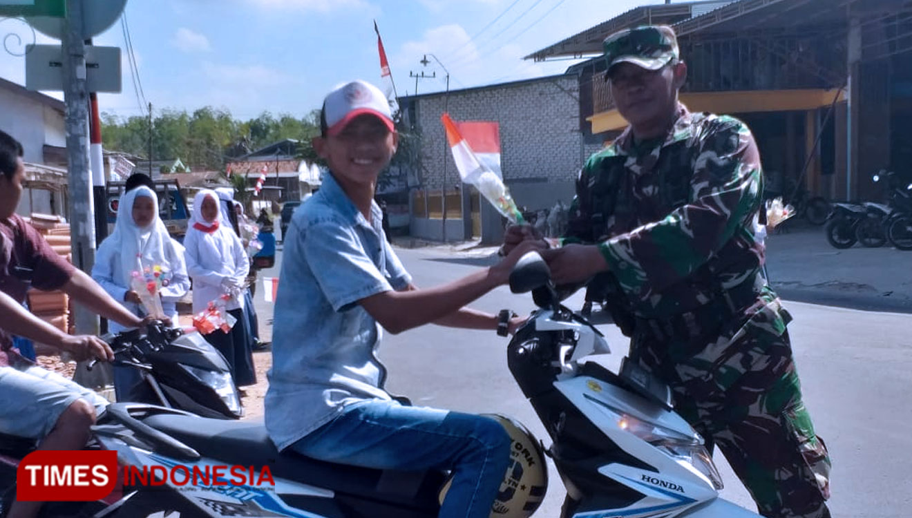 TNI dari Koramil 0826/05 Larangan bersama Santri dan Santriwati saat memberikan bendera di jalan Raya Blumbungan. (Foto: Akhmad Syafi'i/TIMES Indonesia)