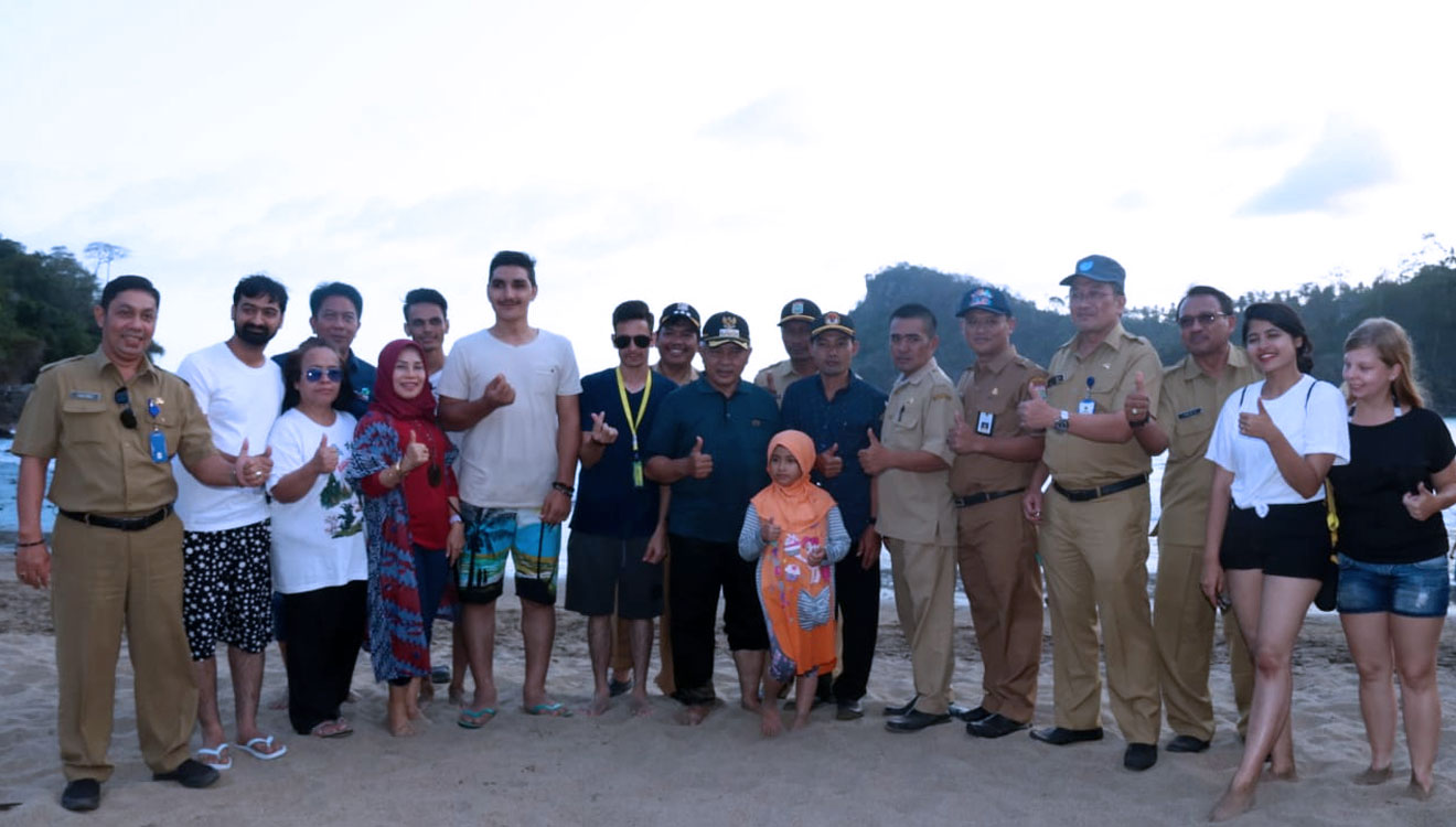 Plt Bupati Malang, Drs HM Sanusi MM saat berfoto bersama mahasiswa asing di Pantai Wedi Awu. (foto : Humas Pemkab Malang for TIMES Indonesia)