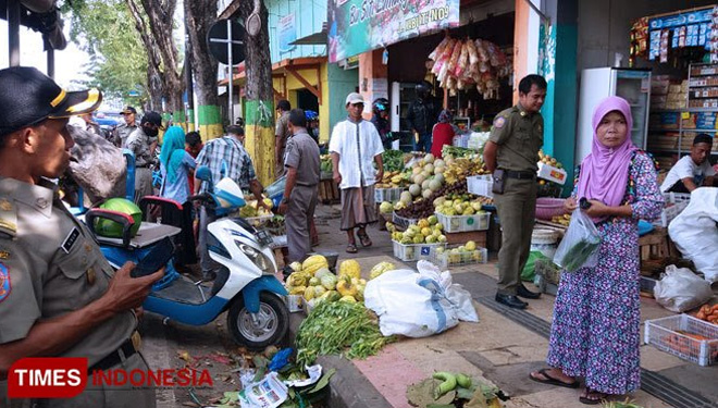 Satpol PP saat melakukan penertiban pedagang di pasar tumpah yang berada di bahu jalan sepanjang Jalan Raya Kabupaten Pamekasan. (Foto: Akhmad Syafi'i/TIMES Indonesia)