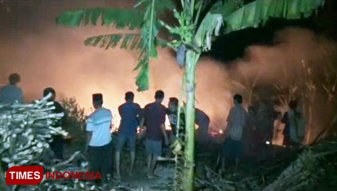 Warga saat berusaha memadamkan api rumah Jemikun. (FOTO: Evita Mukharomah/TIMES Indonesia)
